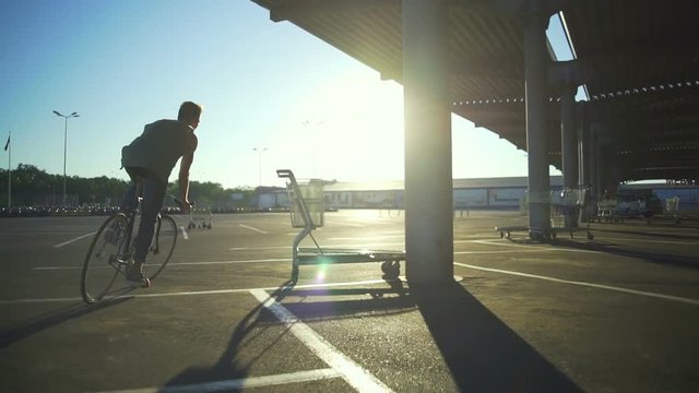 Boy riding bicycle empty car parking circling pillars sunrise slow motion rapid