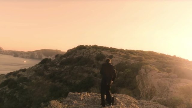 Man In Elegant Suit With Briefcase Walking On Top Of A Cliff On An Island