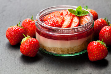 Mini  strawberry cheesecake in a glass pot on black stone background