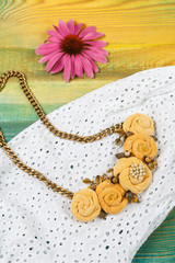 Handicraft necklace lies on the white lace dress background