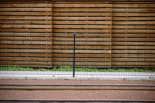 Schienen vor dem Bretterzaun  / Eine neu gebaute Straßenbahnschienenstrecke mit einem Zaun sowie einem Holzbretter Sichtschutz am Rand.