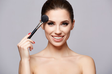 Fototapeta premium Beauty Girl with Makeup Brushes. Make-up for Brunette Woman. Beauty Face with smile