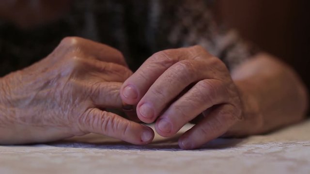 An old widow takes off an engagement ring. The concept of loneliness and grief. Close-up