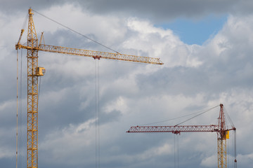 Orange construction tower crane against cloudy sky