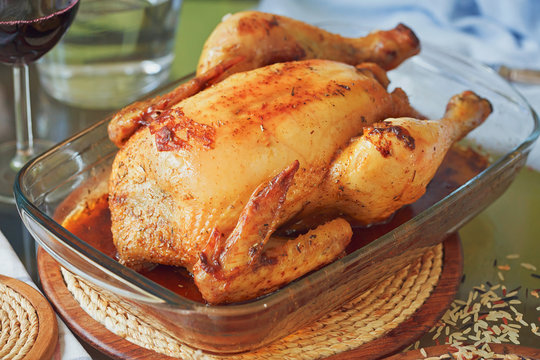 Fresh whole roasted chicken with garlic in glass form for baking
