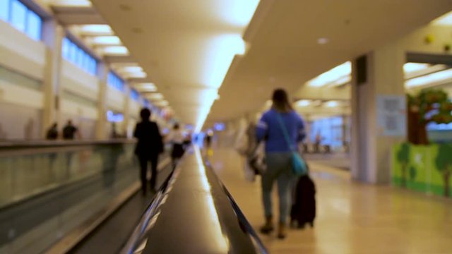 Blurred people moving on flat escalator inside airport terminal