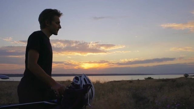 cyclist walk with bicycle helmet field valley dawn seaside slow motion rapid