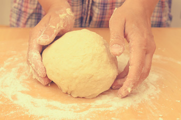 A woman kneads a homemade dough for pizza production.
