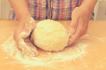 A woman kneads a homemade dough for pizza production.