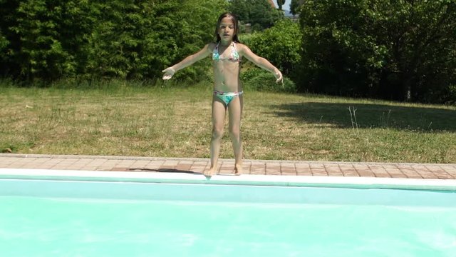 Little caucasian girl jumping in the outdoor swimming pool, slowmo HD