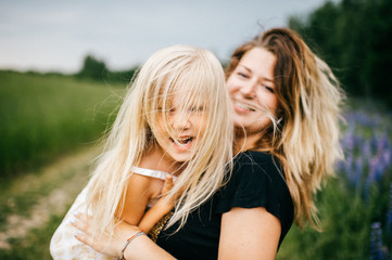 Young mother with long hair holding little daughter princess at hands. Playing with child. Pure, happy, kind, expressive emotional faces. Family at nature. Artistic kid. Laughing, smiling, embracing.