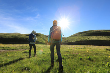 two backpacking women hiking in sunrise mountains