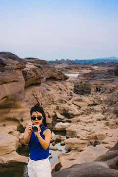 Women with blue shirt taking picture of sunrise in Thailand stone canyon or Sam Pan Boak. Ubonratchathani Province ,Thailand