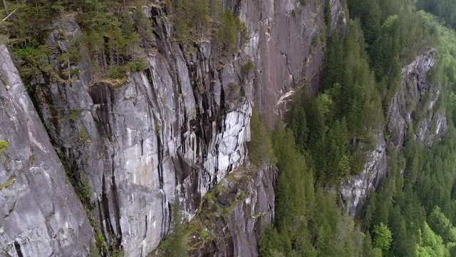 Helicopter View of Massive Mountain Cliffs in Pacific Northwest Wilderness with Evergreen Forest Trees