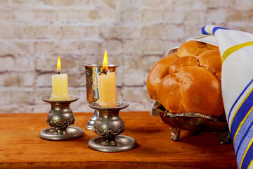 Shabbat candles in glass candlesticks with blurred covered challah