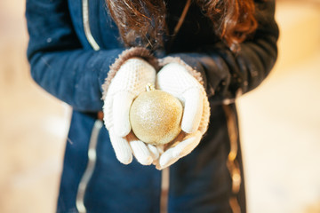 Female hands holding a Christmas gold ball.