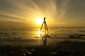 Tripod on the lake with sunrise sky.