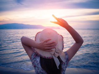 woman holds two fingers or Victory Sign on the beach during sunrise, showing encouragement when we are discouraged.