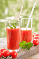 Glasses of fresh tomato juice on wooden table