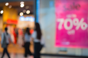 Shopping center with customers and seasonal sale promotions. Blurred, people unrecognizable