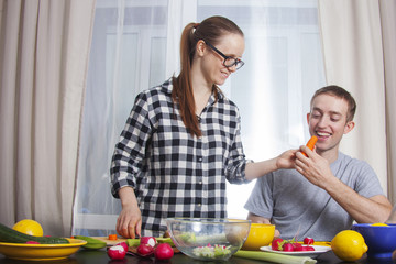 A young couple are cooking their meal
