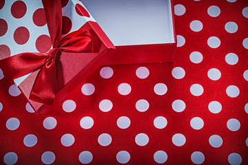 Opened present box with bow on polka-dot red fabric celebrations