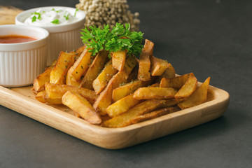 Homemade french fries serve with ketchup and sour cream or mayonnaise. Golden brown crispy french fries sprinkle with salt and oregano on plate for snack or appetizer. French fries on granite table.