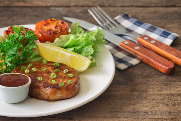 Barbecue pork steak on white plate served with barbecue sauce and vegetables. Pork steak for lunch or dinner on wood table. Moist and soft homemade pork barbecue served with mash potato and vegetable.
