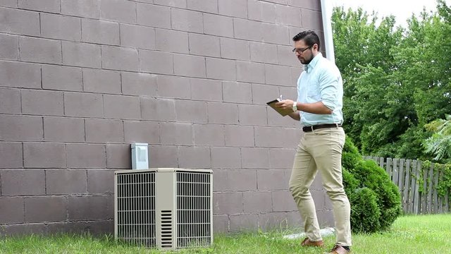 Young Home inspector or Contractor takes notes of an old AC unit