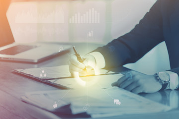 businessman signs a contract with business icons. Focus on the pen holding in hand - Business Concept