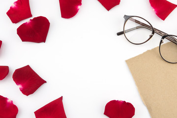 Blank brown card and glasses decorated with red rose petals with copy space in the center on white background