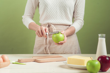 Fototapeta na wymiar House wife wearing apron making. Steps of making cooking apple cake. Cutting green apple.