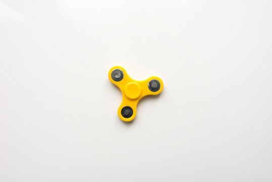 Yellow  Hand Spiner. Stress relieving toy on white background. Close-up. Top view. Stock photo
