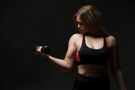 Confident young woman posing with dumbbell