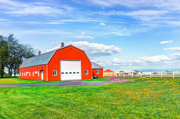 Red orange painted barn shed with white doors in summer landscape field in countryside - Powered by Adobe
