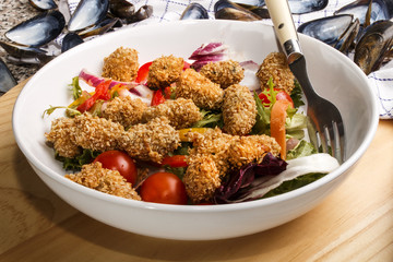 breaded mussels with fresh salad in a deep dish