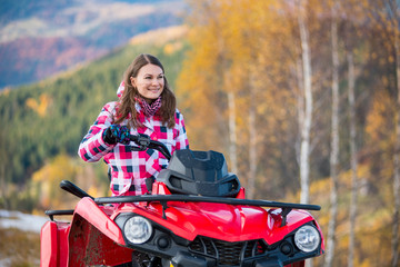 Fototapeta na wymiar Close-up portait of happy girl in winter clothing on red quad bike in the autumn nature