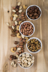 Four bowls with nuts on a  wooden table.