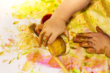 Painted hands smudging colors on messy table