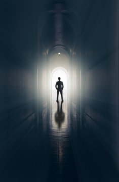 Businessman is standing in the end of tunnel with the ray light and effect filter, Abstract business, finding the way out successful concept and low key lighting.