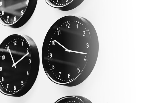 multiple time clock on the wall black and white with space for text.