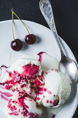 Homemade ice cream with sherry and berries on a plate over black concrete background