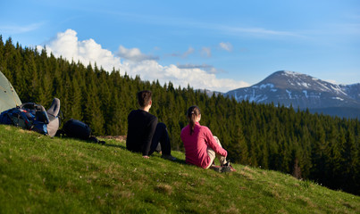Rearview shot of two female hikers sitting near their tent and backpacks enjoying beautiful mountains view copyspace lifestyle activity sport health friendship travelling evening