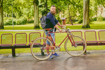 Redhead bearded male on a retro bicycle in a park.