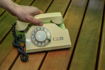 Old beige disk phone on wooden background