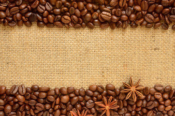 Whole roasted coffee beans at top and bottom of coarse cloth with stars anise