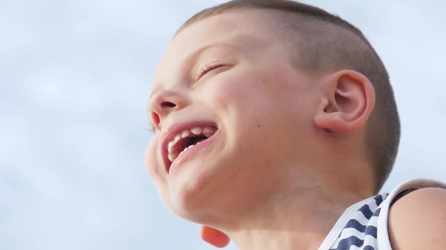 Funny happy smiling boy singing a song on sky background