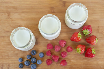 Three glass jars with yogurt and variation of berries - directly above
