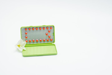 Birth control pills with modern packaging and flower on white background