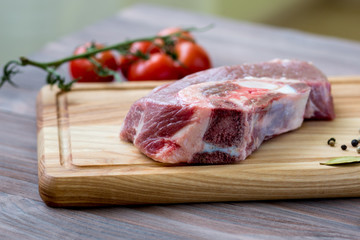 Fresh meat on the wooden table with spices and tomatoes